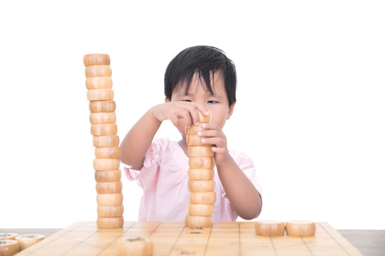 小女孩桌子上摞中国象棋棋子