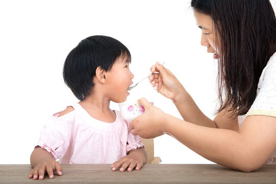 年轻妈妈正给可爱的女儿喂饭