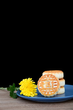 桌子上一盘月饼和一朵菊花