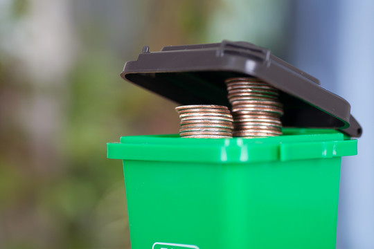 冒出美元硬币的绿色垃圾桶模型