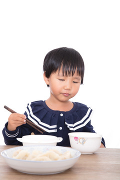 中国小女孩坐在桌子前吃饺子