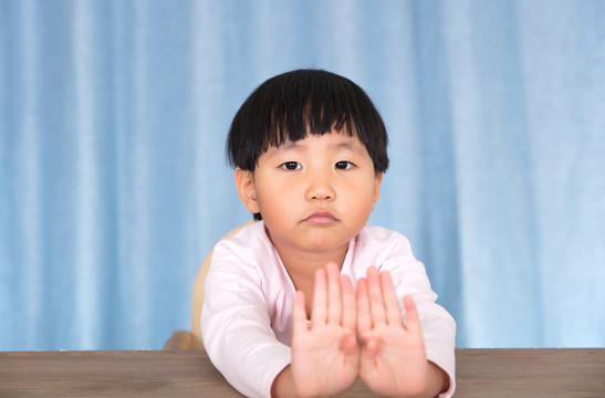 小姑娘看着镜头双手做拒绝的手势