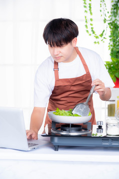 青年男性边看视频教程边做饭