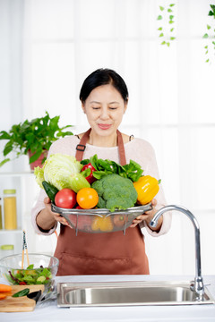 女性在厨房端蔬菜准备做菜