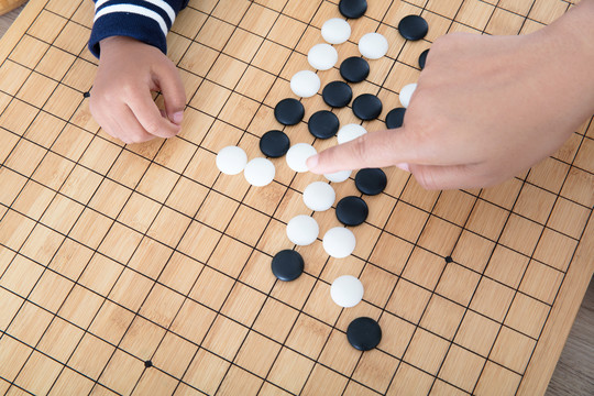 大人的手指导着小孩的手下围棋