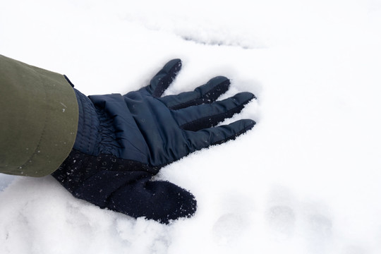 一只带着手套的手摸在雪地上