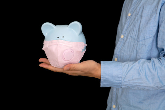 男士手托一个戴口罩的小猪存钱罐