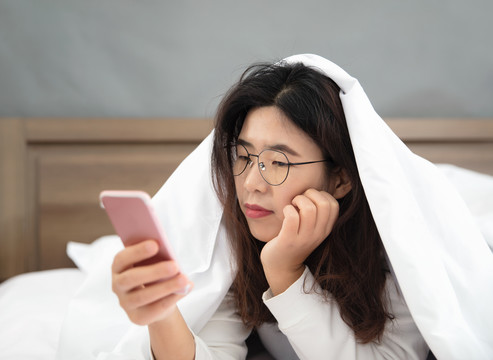 懒散的中国女孩床上玩手机