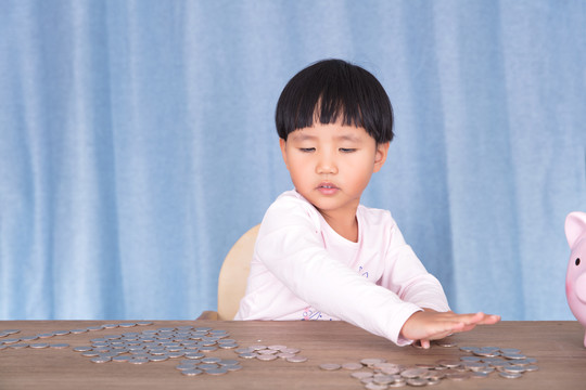 小女孩在摆弄桌子上的美元硬币