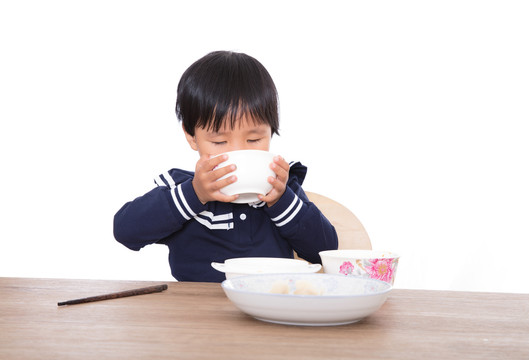 饥饿的黄皮肤小女孩在大口喝汤