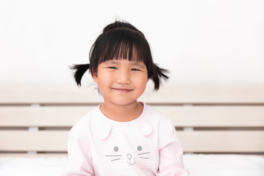 可爱的亚洲小女孩坐在床上的肖像
