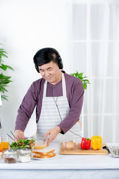 老年男士在厨房边听音乐边做饭