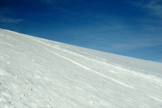 寒冬的蓝天下积满白雪的山坡