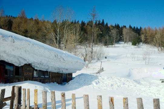 寒冬蓝天下积满厚雪的山村木屋
