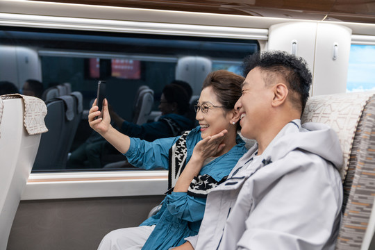 快乐的老年夫妇坐地铁用手机自拍