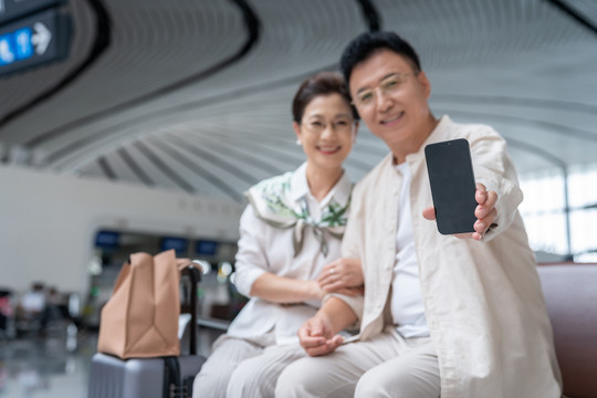 快乐的老年夫妇在机场展示手机