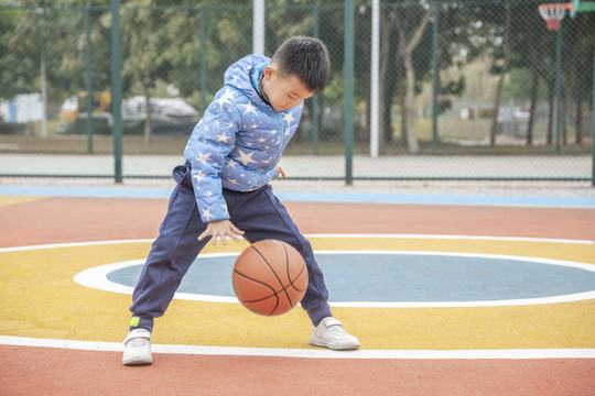 学校操场上打篮球的小男孩