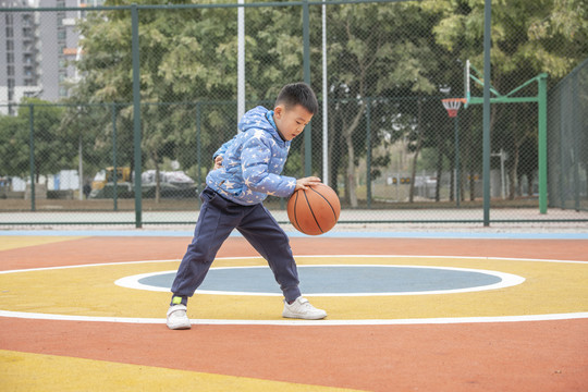 学校操场上打篮球的小男孩