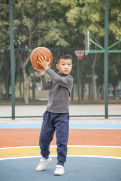 学校操场上打篮球的小男孩