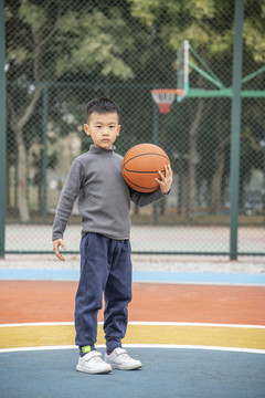 操场上抱着篮球的少年