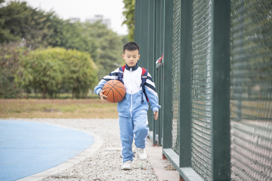 操场上抱着篮球的小学生