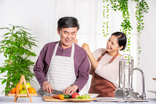 老年夫妻在厨房做饭捶肩