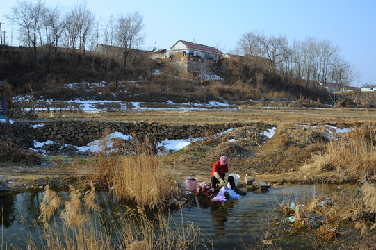农村女人在冬天的河边洗衣服