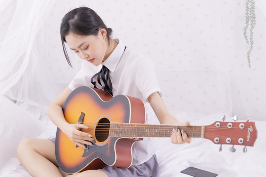 室内女性在床上弹吉他