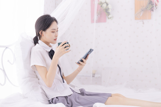 床上玩手机的年轻东方女性