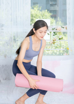 室内女性整理瑜伽垫