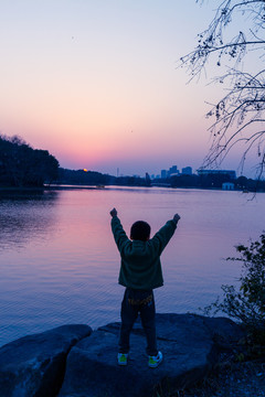 夕阳下湖边的男孩背影