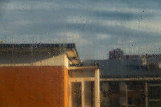 窗上雨痕后建筑上的阳光