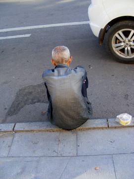 路边坐着一个干瘪的老人