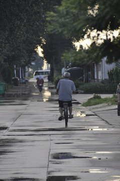 雨后在路上骑行的老人