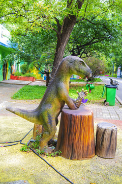 倚树墩立着的恐龙雕塑像
