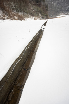 水渠将积雪覆盖的田园分成两块