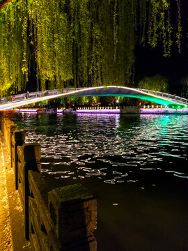 夜晚河畔垂柳和灯带闪耀的长桥