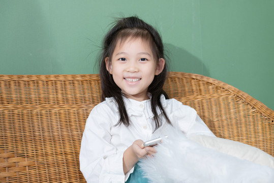 躺椅上微笑玩手机的小女孩