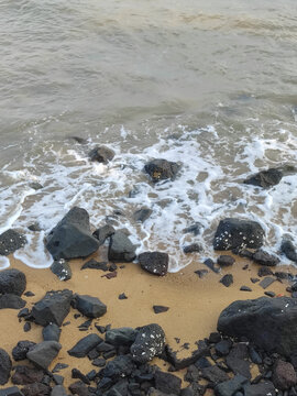 黑石头黄沙滩白海浪黄浑浊海水