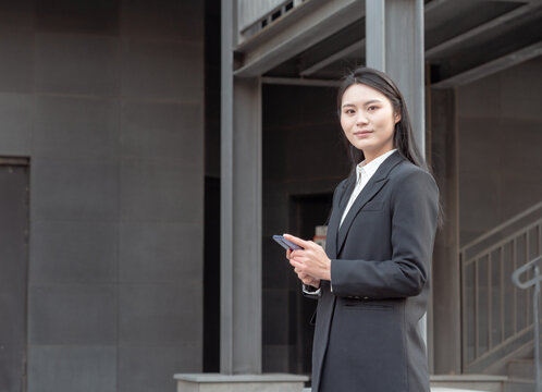 街头使用手机的西装女性