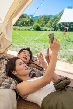 情侣躺在帐篷里看手机