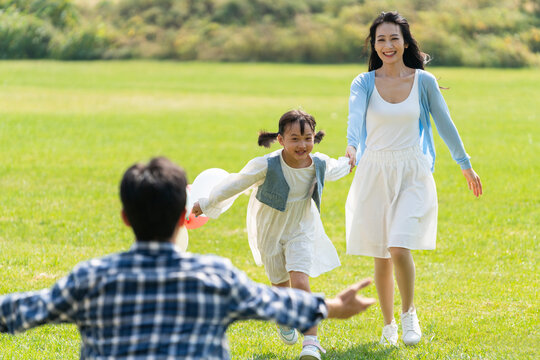 妈妈和女儿开心地跑向爸爸的怀抱