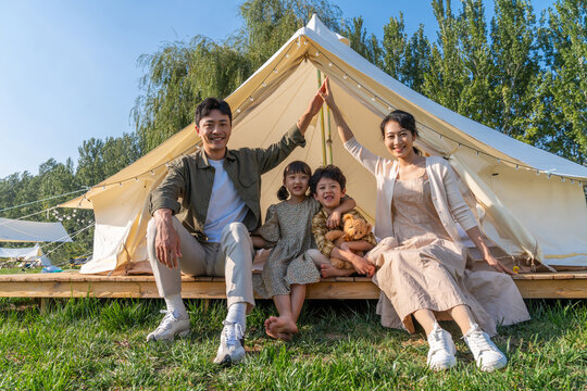 一家人坐在露营地的帐篷前