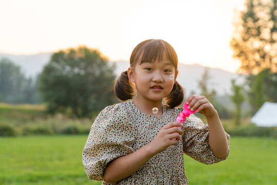 一个小女孩在草地上吹泡泡