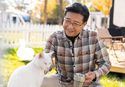 一个老年男人蹲着和猫玩耍