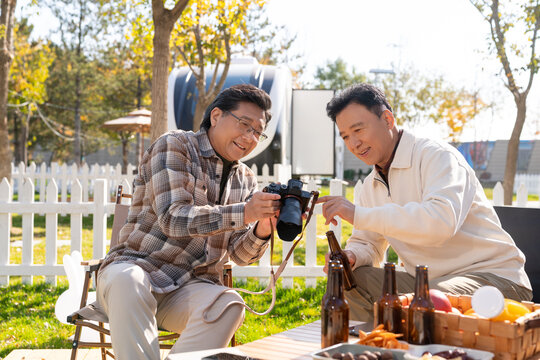 两个老年男人坐在露营地看数码相机