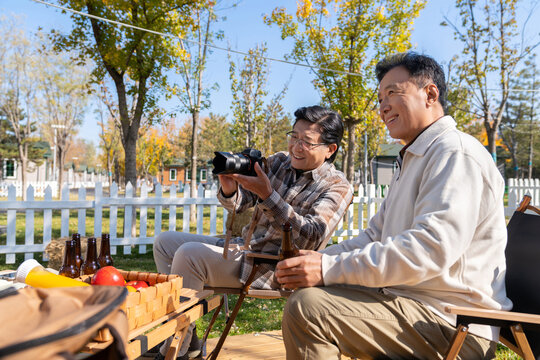 两个老年男人坐在露营地看数码相机