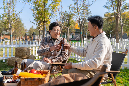 两个老年男人坐在露营地喝啤酒