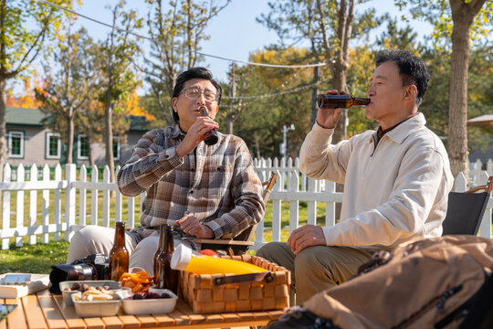 两个老年男人坐在露营地喝啤酒