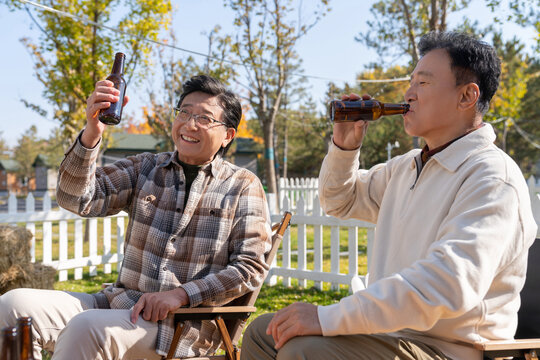 两个老年男人坐在露营地喝啤酒